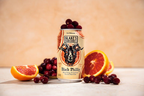 A can of Blake's Black Phillip hard cider with blood orange slices and cranberries