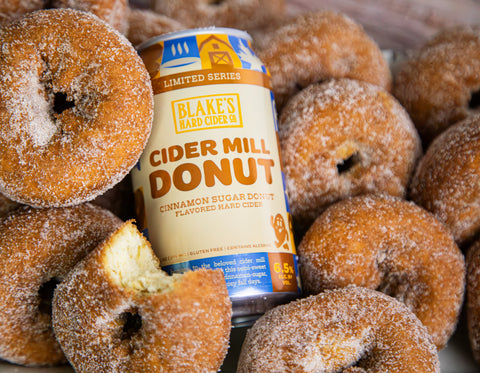 A can of Blake's Cider Mill Donut hard cider resting on cinnamon sugar donuts