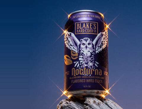 Blake's Hard Cider Nocturna can on a weathered log under a night sky