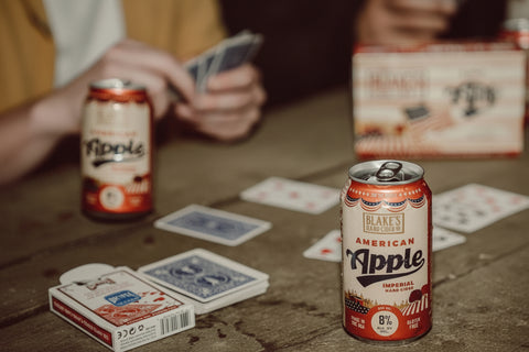 Friends playing cards with cans of Blake's Hard Cider American Apple